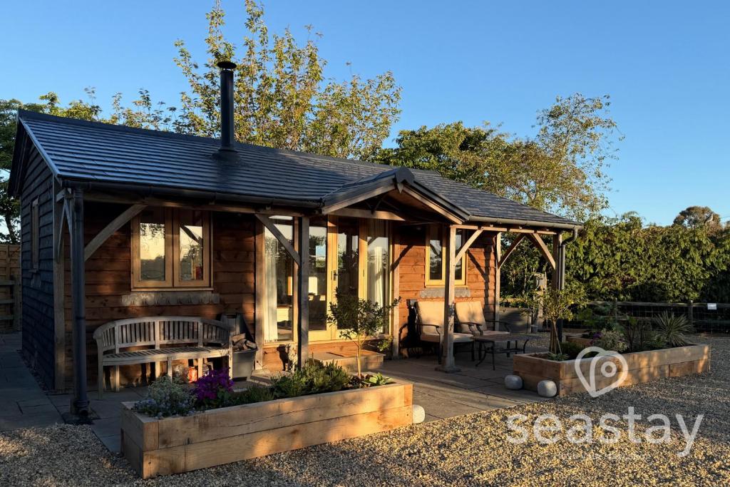 a wooden cabin with a roof on a patio at The Gatehouse Lodge Farm Stay, Distant Sea Views in Deal