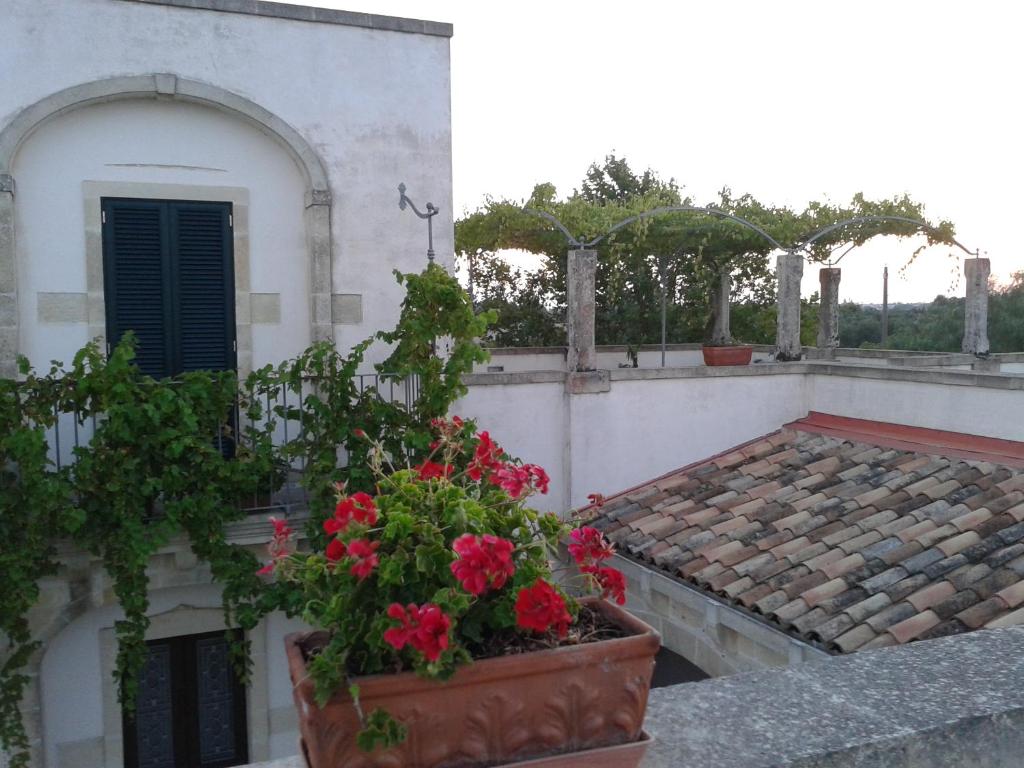 un balcón con flores rojas en un edificio en Corte dei Salentini, en Carpignano Salentino