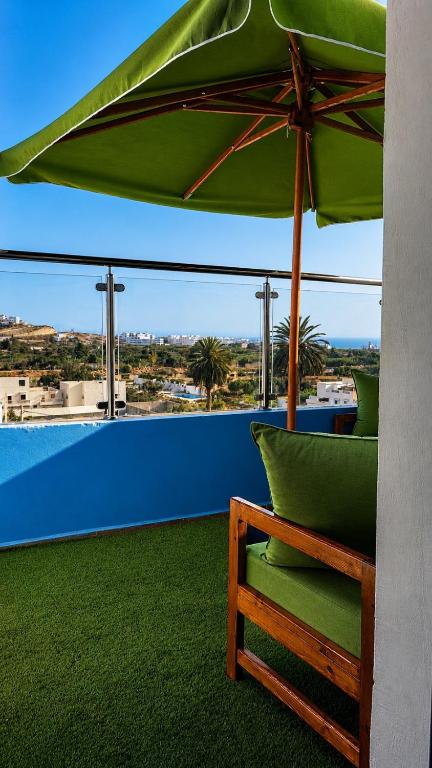 a green umbrella and a bench on a balcony at House Aisha Rooftop Hostel in Aourir