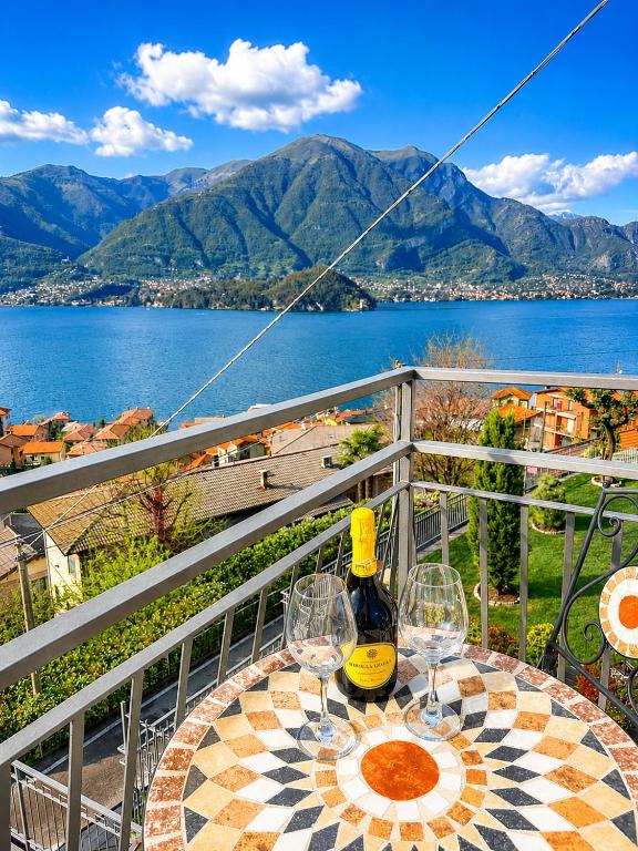 a table with wine glasses and a bottle on a balcony at Little house Lezzeno in Lezzeno