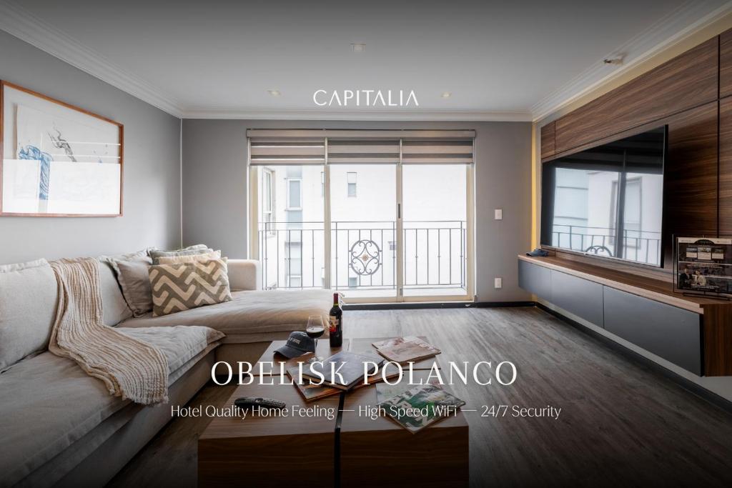a living room with a couch and a large window at Capitalia Obelisk Polanco in Mexico City