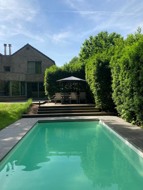 a swimming pool with a table and an umbrella at Magnolia in Wuustwezel