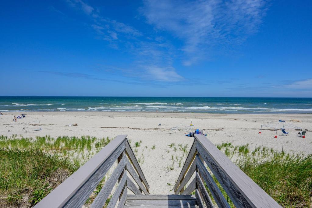 a view of a beach with the ocean and a wooden staircase at East Sandwich Beachfront Retreat in East Sandwich