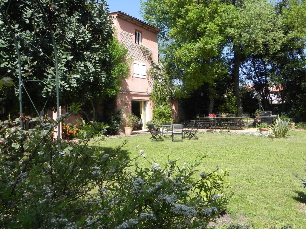 un giardino con tavoli e sedie di fronte a un edificio di B&B Le clos des vignes Saint Raphael a Saint-Raphaël