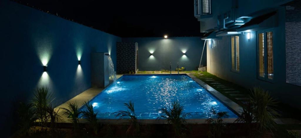 a swimming pool at night with lights in a house at Pearl Beach Resort in Covelong