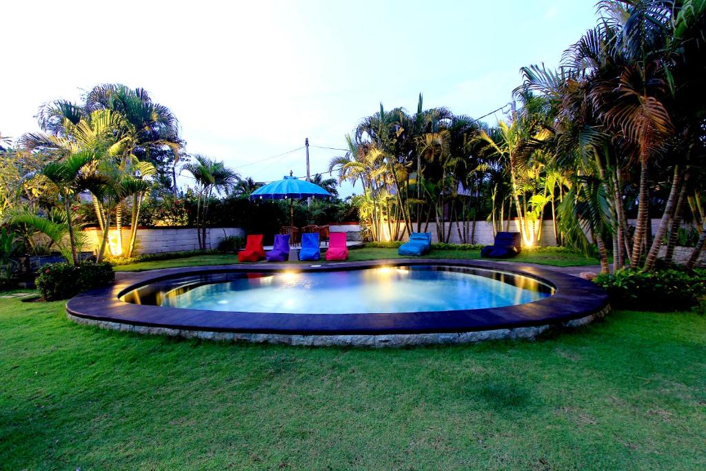 una piscina en un patio con sillas y sombrilla en Alamanda Bingin, en Uluwatu