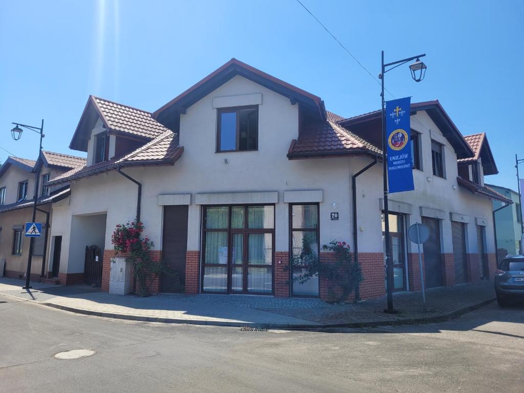 a white building with a brown roof on a street at Pokoje Optima in Uniejow