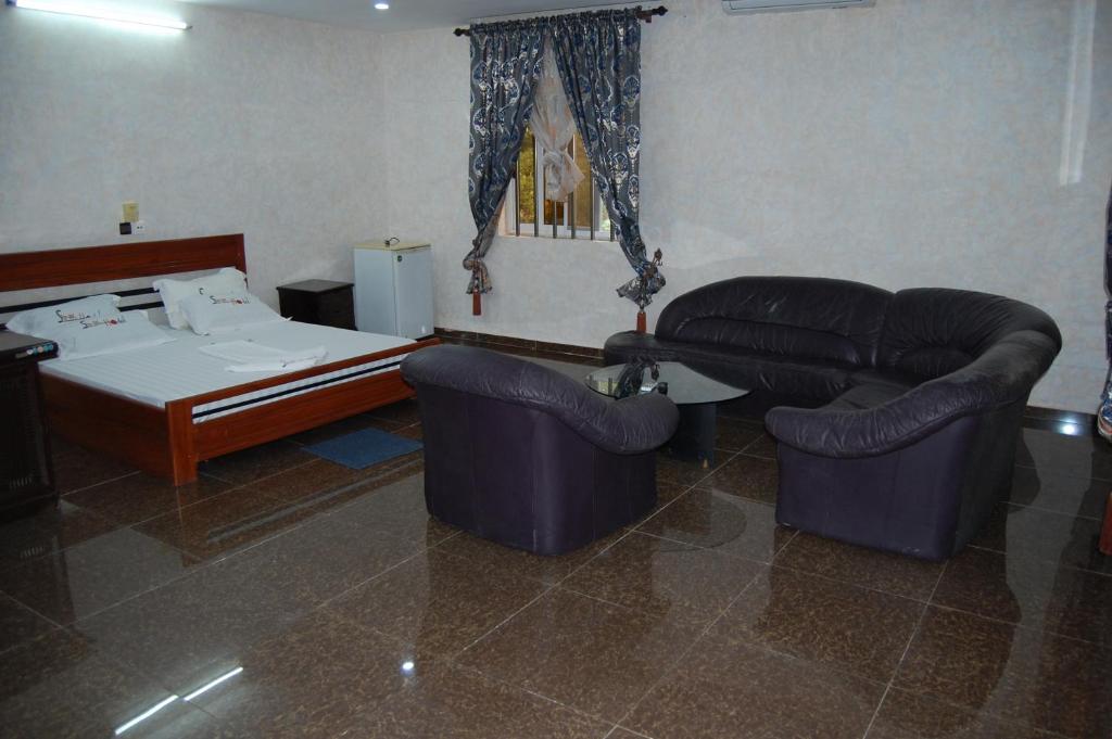 a bedroom with a bed and two couches and a table at Link Hotel in Lokossa