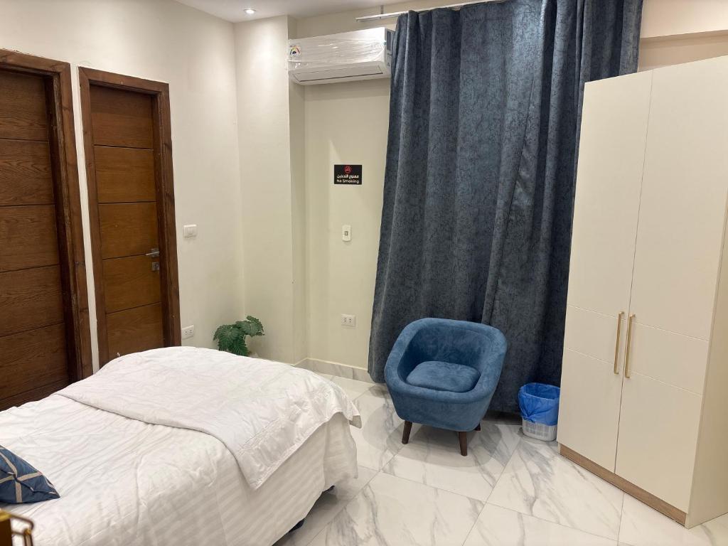 a bedroom with a bed and a blue chair at Dera October city in 6th Of October