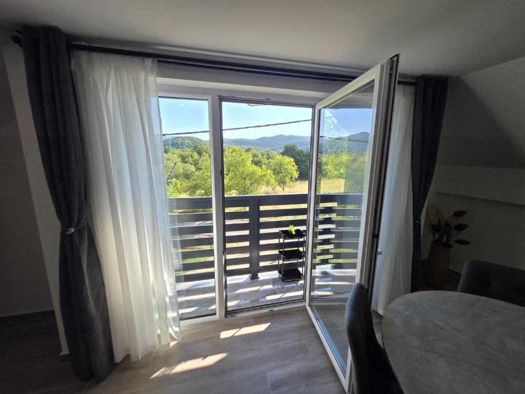 a bedroom with a large sliding glass door to a balcony at UP & DOWN Holiday House in Donji Prozor