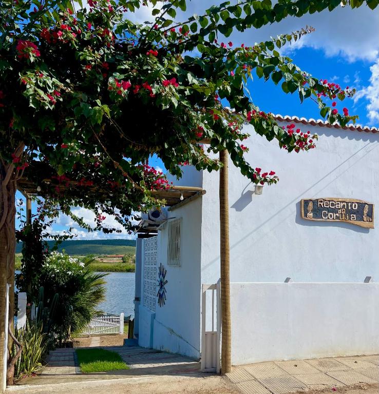 a white building with a sign that reads next to a lake at Chalé Recanto da Coruja in Pão de Açúcar
