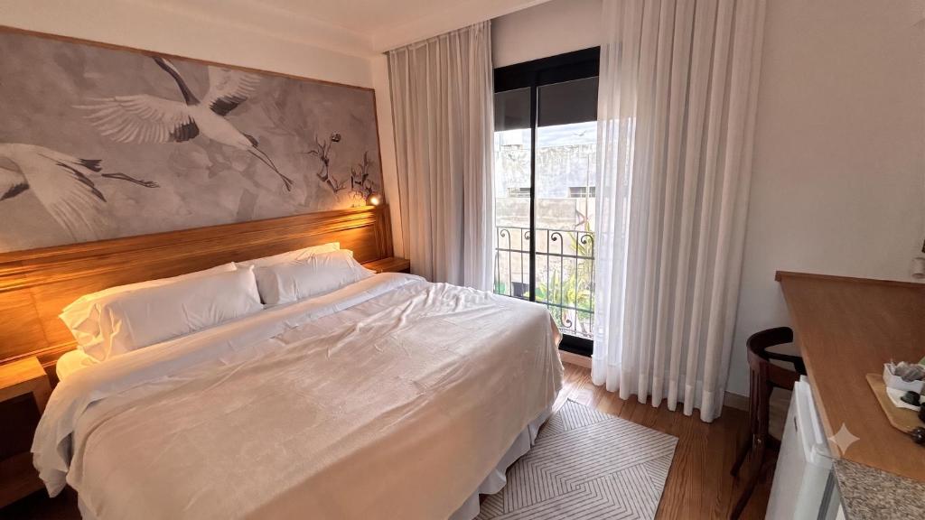a bedroom with a large white bed and a window at Le Flâneur Boutique Hotel in Pergamino