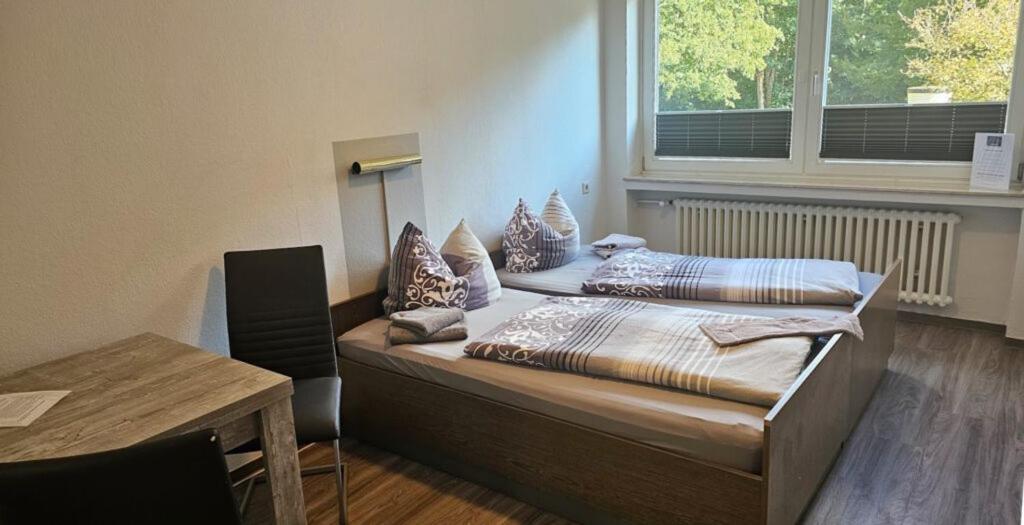 a bedroom with two beds and a table and a window at Wolfcenter Gästezimmer in Dörverden
