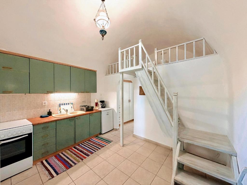 eine Küche mit grünen Schränken und einer Wendeltreppe in der Unterkunft Volta Stonehouse Apartments in Frátsia
