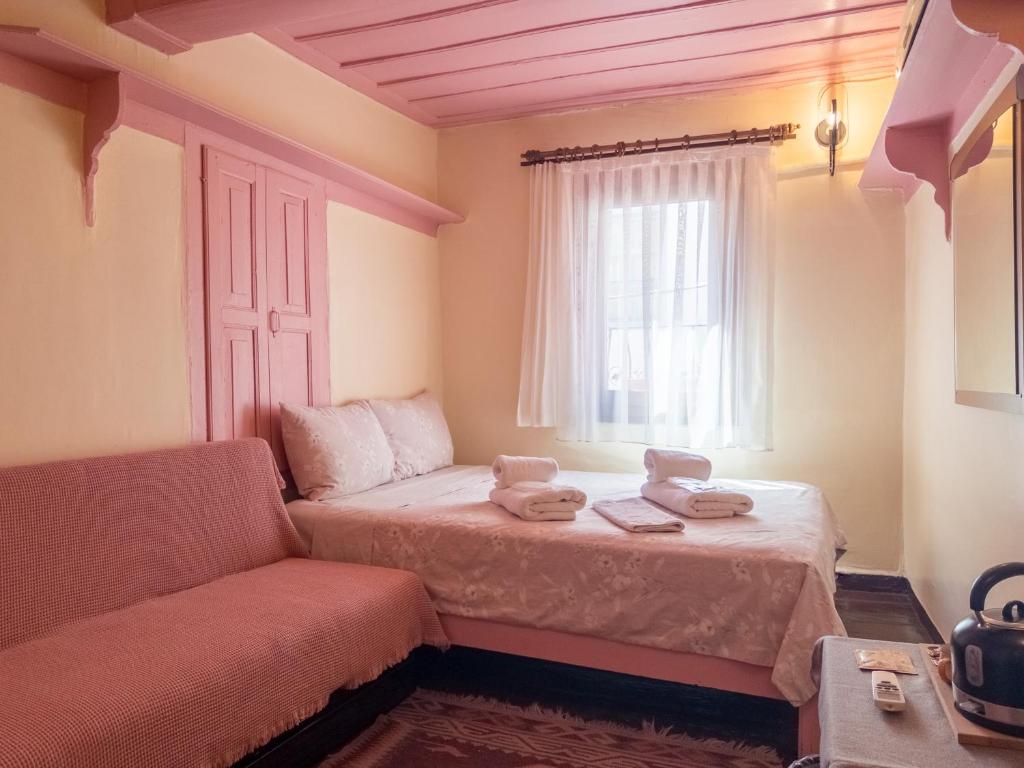 a bedroom with a bed and a couch and a window at Tarihi Rum Konağı Antikhan in Ayvalık