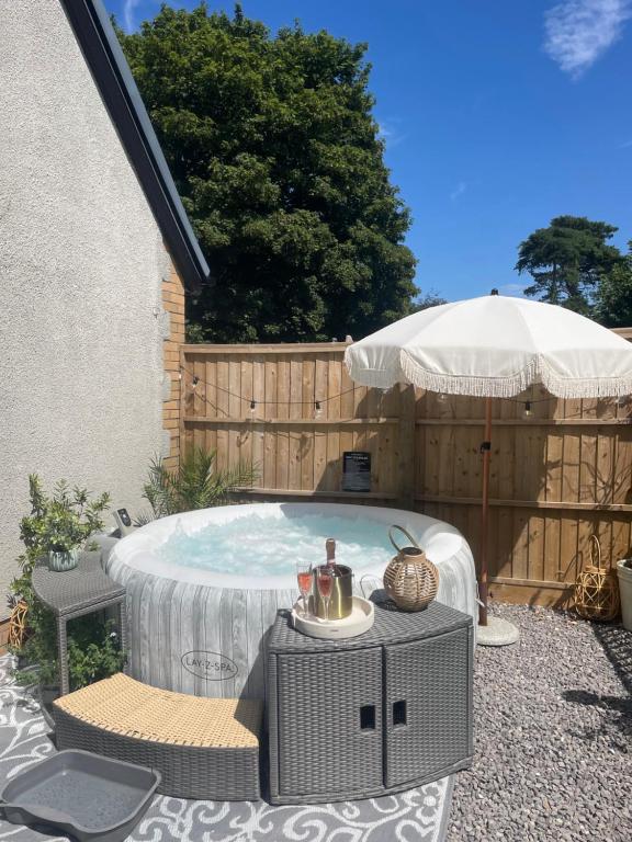 a backyard with a hot tub and an umbrella at Breach Lodge in Bonvilston