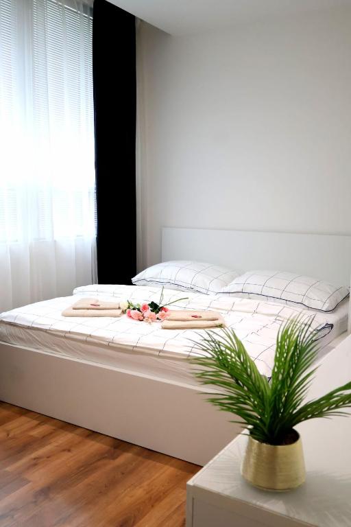 a white bed with two plates and a plant on it at Apartman Deluxe Astrova B in Bratislava