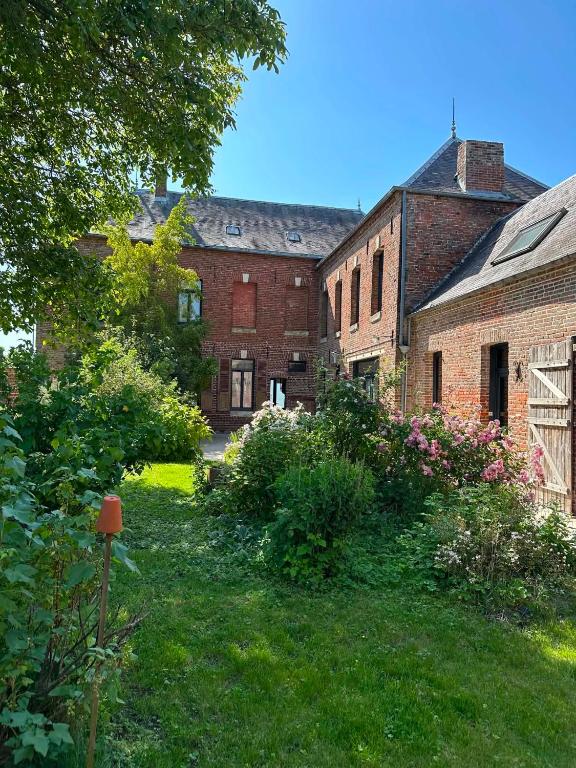 a group of old brick buildings in a yard at La Loge Appartement 1 in Beauquesne