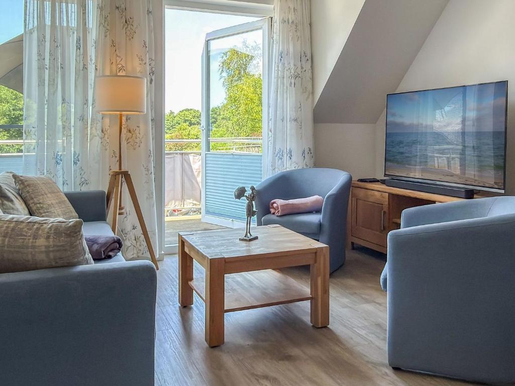 a living room with two blue chairs and a tv at Tordalk 09 in Prerow