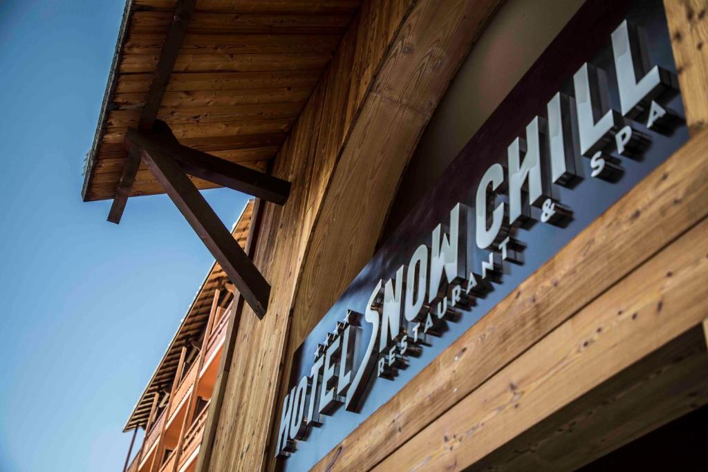 a sign on the side of a building with a cross at Hotel SNOW CHILL in Risoul