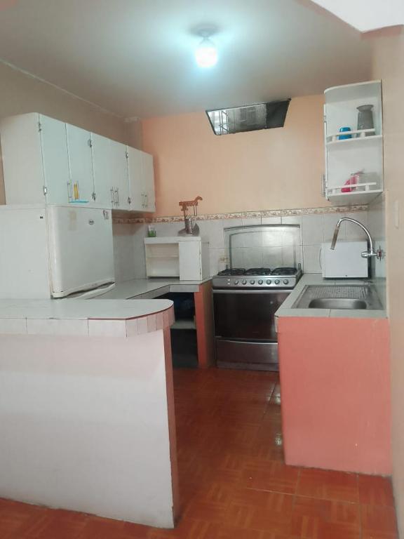 a kitchen with white cabinets and a black stove at Alojamientos La Escapadita in Manta