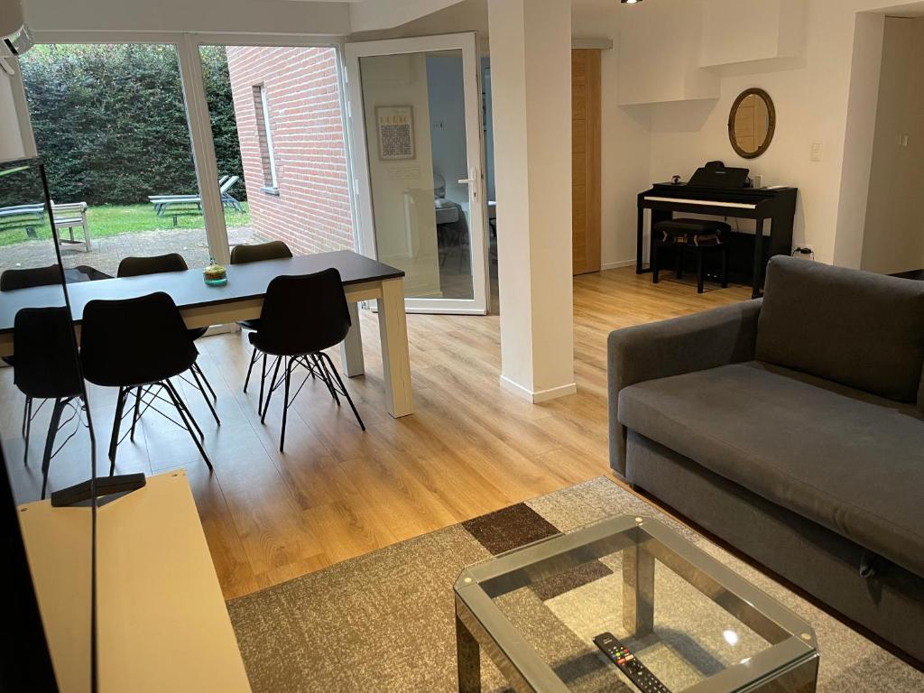 ein Wohnzimmer mit Sofa, Tisch und Klavier in der Unterkunft Hoeilaart in Hoeilaart