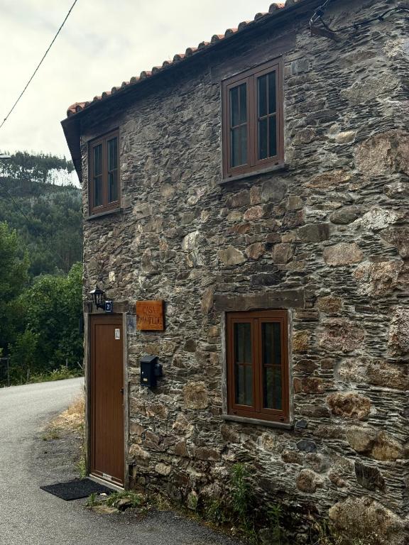 a stone house with a door and windows on a road at Casa D Matilde in Góis