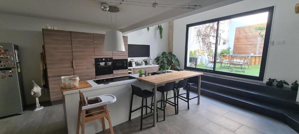 a kitchen with a counter and a table with bar stools at Maison Loft atypique - Jacuzzi clim et jardin in Saint-Jean-de-Védas