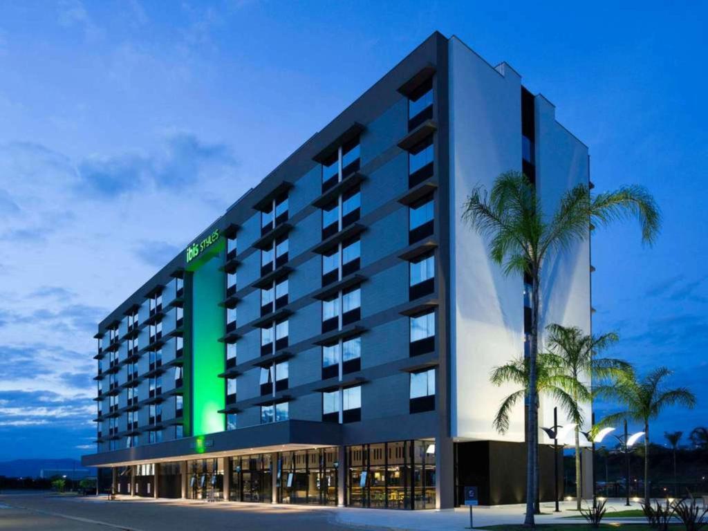 a large building with a palm tree in front of it at ibis Styles Taubate in Taubaté