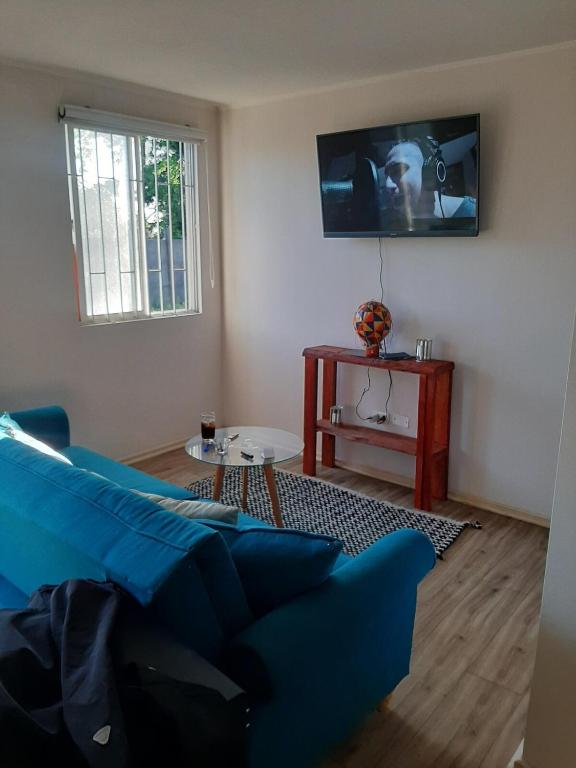 a living room with a blue couch and a tv at Depto Condominio Buena Vista in Coronel