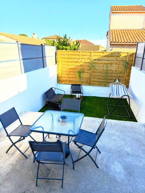 a patio with a table and chairs and a fence at Entre Terre et Mer, logement cosy in Poussan