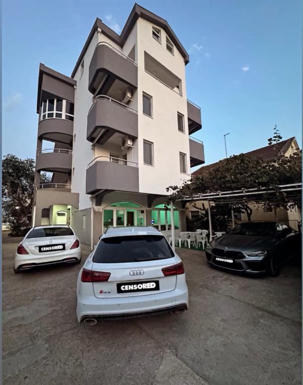 two cars parked in a parking lot in front of a building at Vila Vienna in Donji Štoj