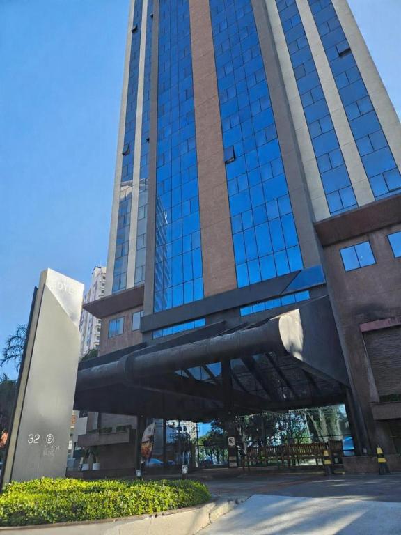 a tall building with blue windows in a city at Guarulhos Flat Hotel in Guarulhos