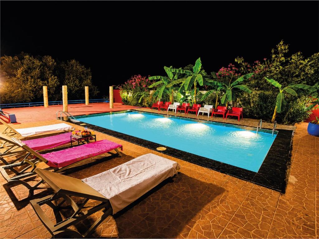 a swimming pool with chaise lounge chairs and a resort at Riad Belgika Marrakech in Ourika
