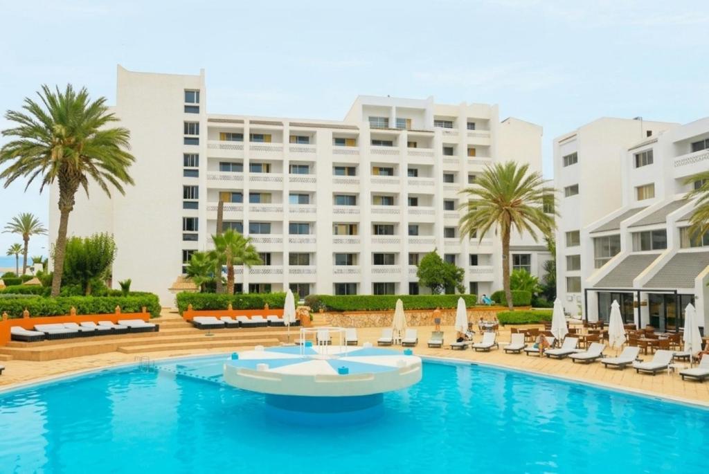 a swimming pool with chairs and a hotel at HAMILTON Agadir in Agadir