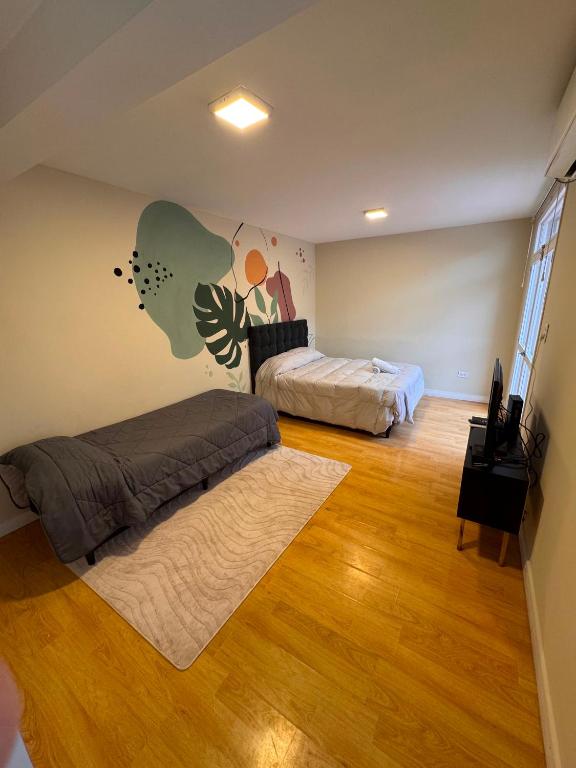 a bedroom with two beds and a wooden floor at Mendoza Centro Apartment in Mendoza