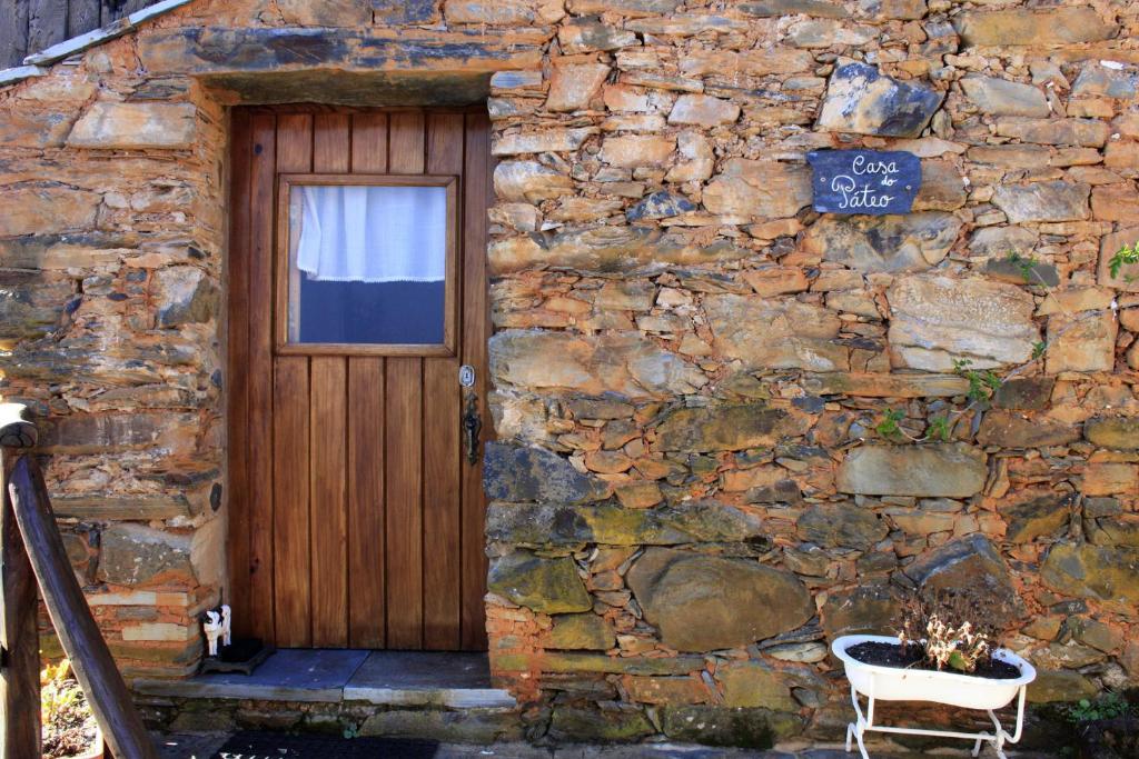 un edificio de piedra con una puerta de madera y un gato en la parte delantera en Vilar dos Condes, en Madeirã