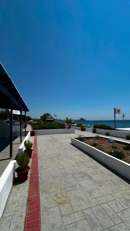 a walkway with potted plants and the ocean in the background at Syrtaki Studios in Kámpos