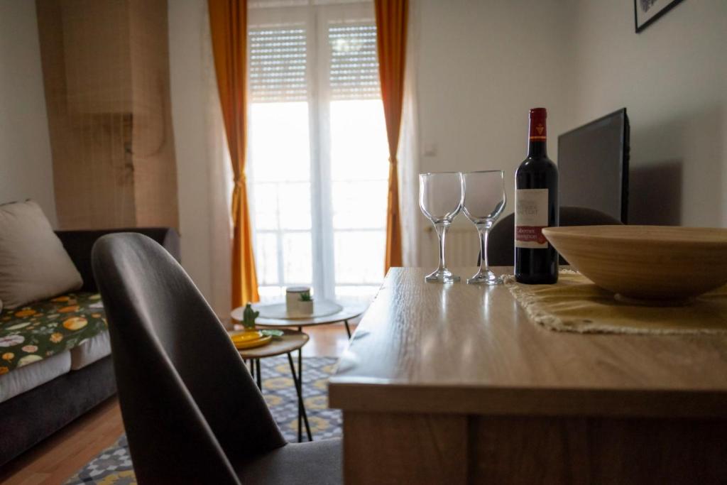 a living room with a bottle of wine and two wine glasses at VukaNest apartman Jagodina in Jagodina