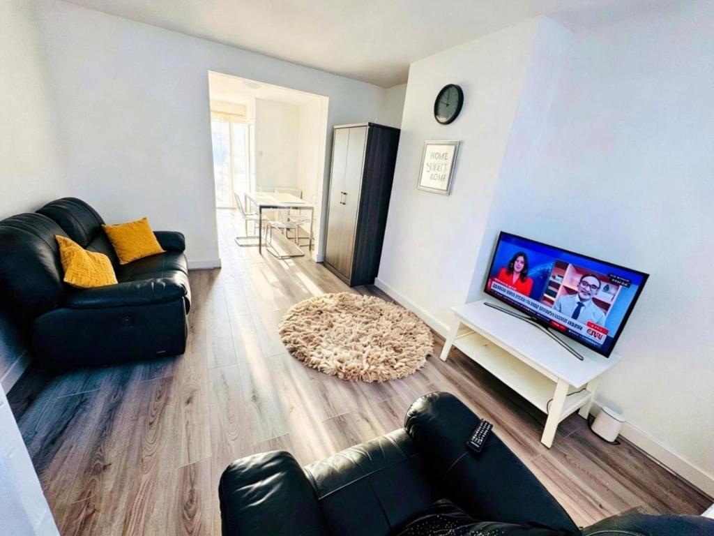 a living room with a couch and a flat screen tv at The Heath Haven- Morden 4 Bedroom House Near Station High Street, Free Parking WiFi in Goodmayes