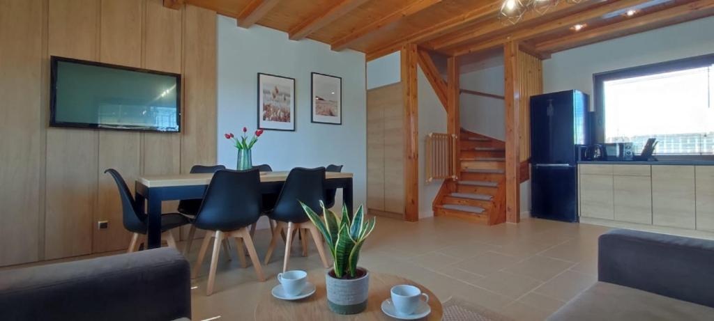 a living room with a table and chairs and a kitchen at Domki Malibu in Tupadła