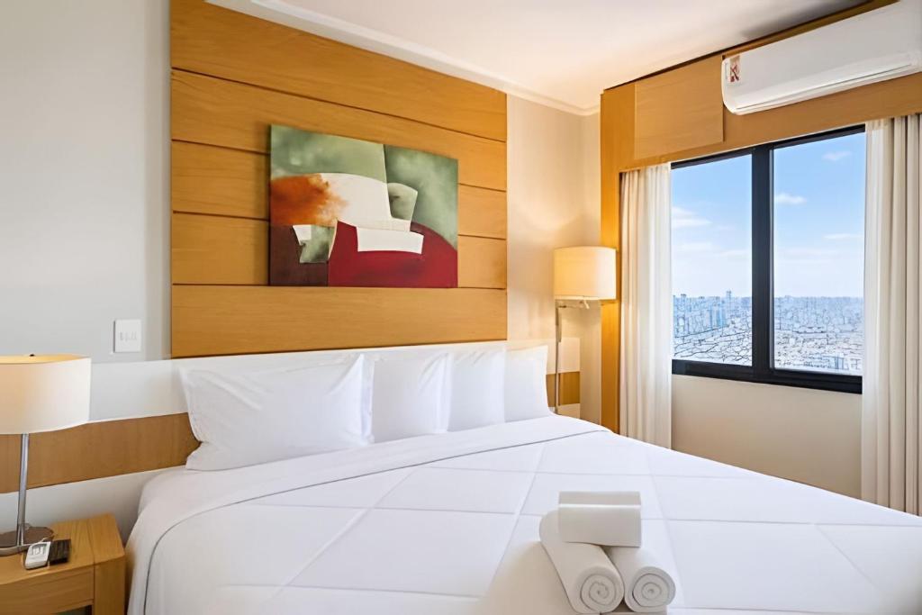 a bedroom with a white bed and a window at Flat Moderno em Congonhas com sofá-cama 1113 in São Paulo