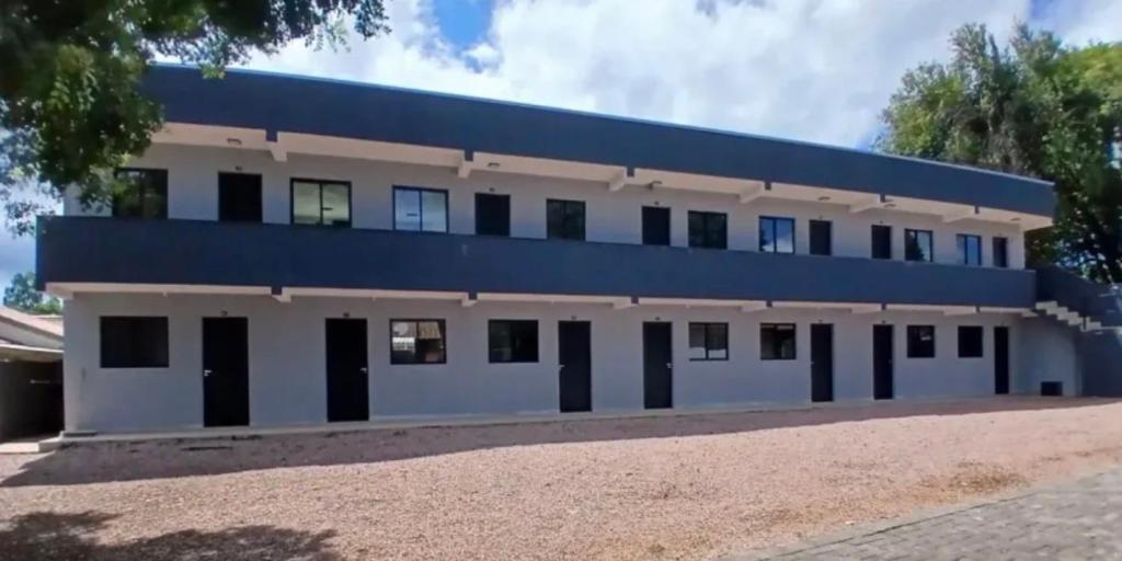 a large white building with a blue roof at Studios Carambeí in Carambeí