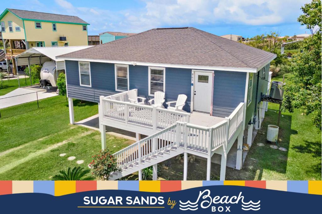 a blue house with a deck with chairs on it at Cozy and charming getaway with deck, close to beach in Crystal Beach
