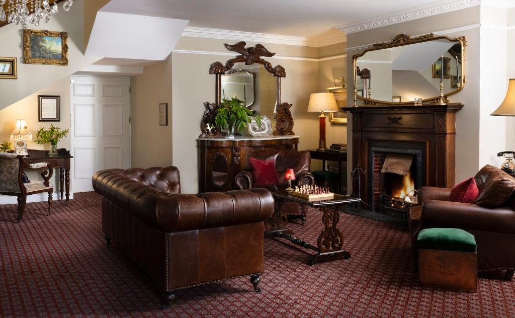 a living room with a leather couch and a fireplace at Earls Court House in Killarney