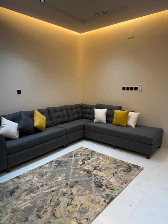 a living room with a black couch and yellow pillows at شقق ورد in Al Barkah