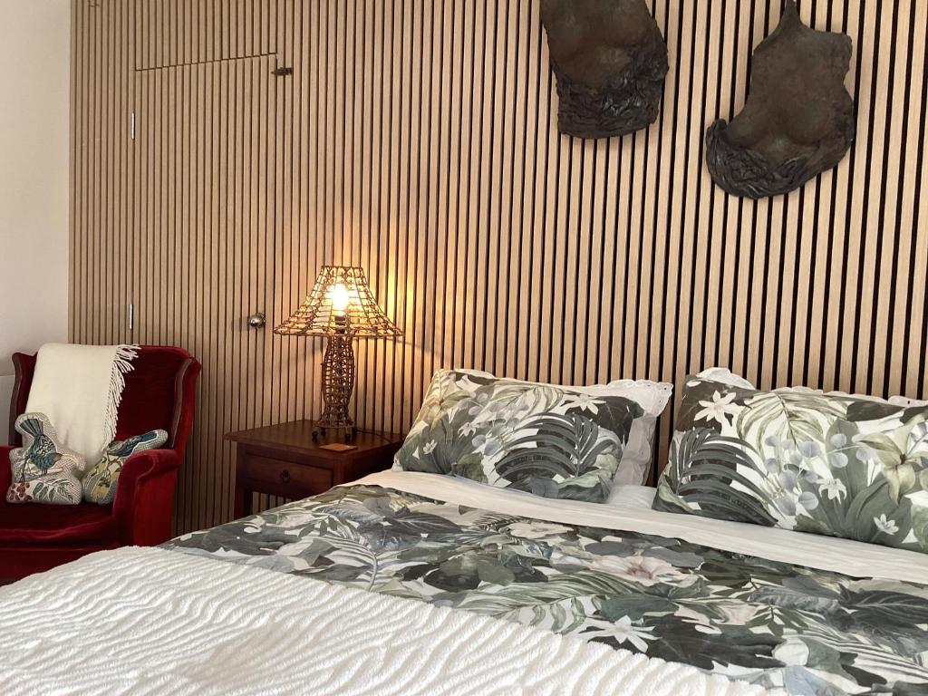 a bedroom with a bed and a lamp and a chair at Driftwood Sands Studio in Tairua