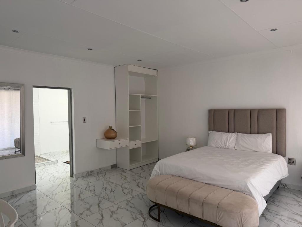 a white bedroom with a bed and a mirror at Veesboutiquehotel in eMalahleni