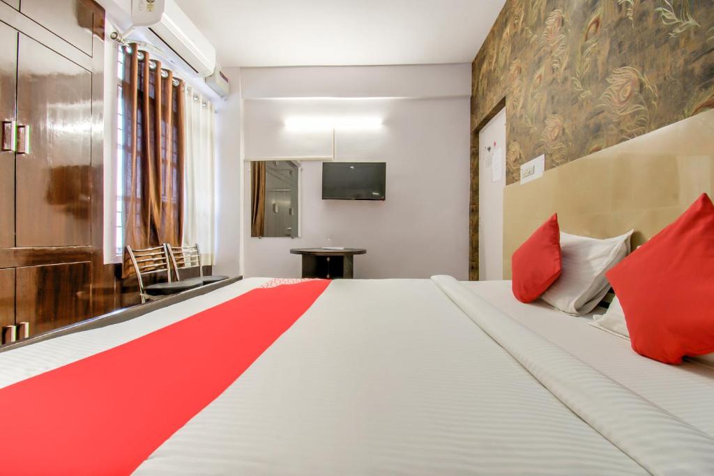 a bedroom with a large white bed with red pillows at Hotel O Kamini in Patna