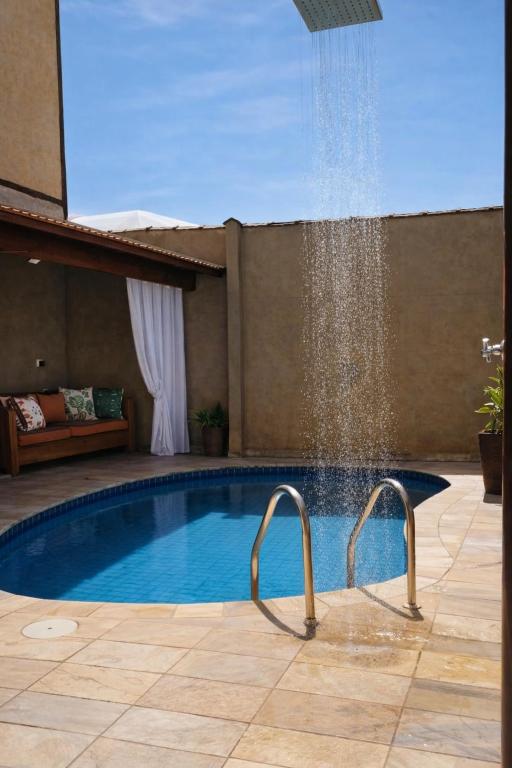 a swimming pool with a water fountain at Chalé de Charme Mandomai in Ilhabela